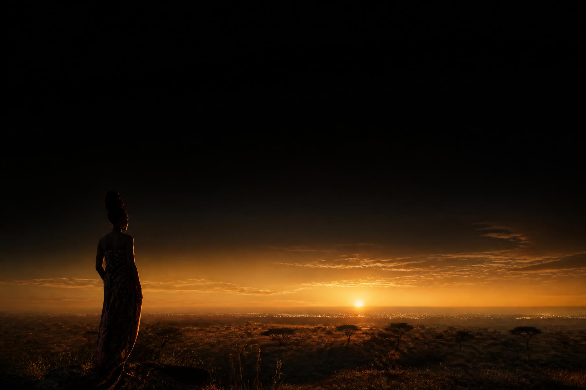 A young African woman looking toward a golden dawn
